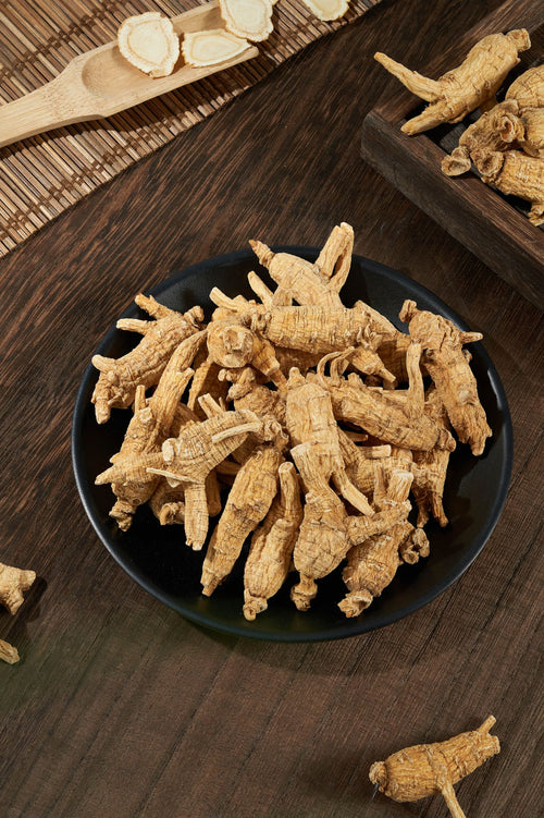 Dried roots in a dark bowl on a wooden board